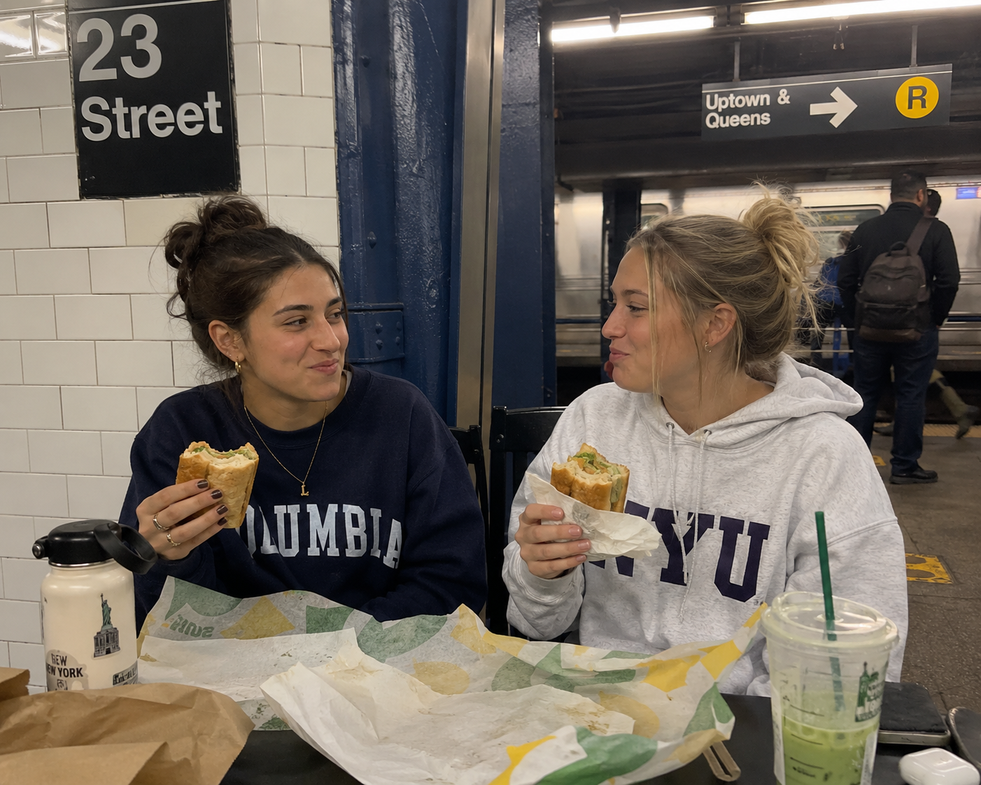 Friends eating sandwiches on a subway platform
